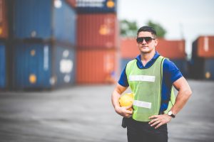 Young male warehouse supervisor wearing eyeglasses and vest supervising work